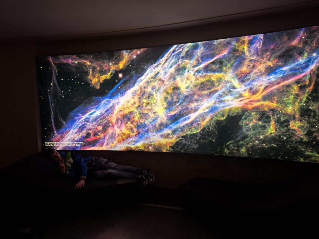 Uczeń leżący pod wyświetlanym obrazem kosmosu